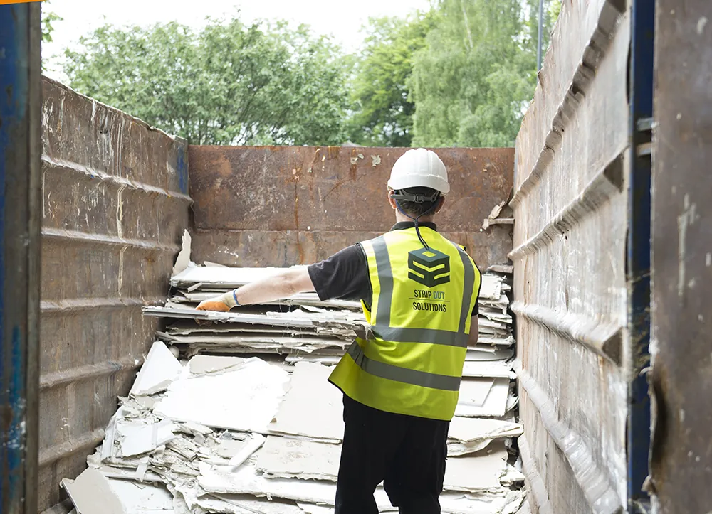 An SOS operative loading strip out waste into a skip
