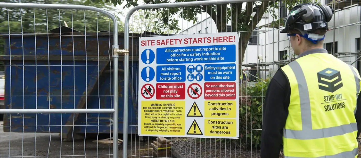 An SOS supervisor checking site safety signage at the gate