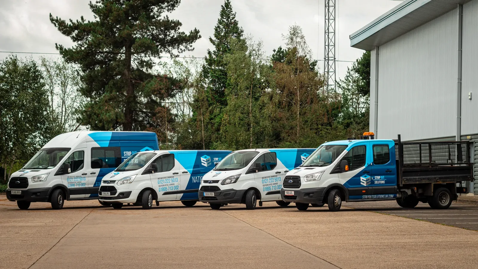 The Strip Out Solutions liveried van fleet lined up outside a warehouse